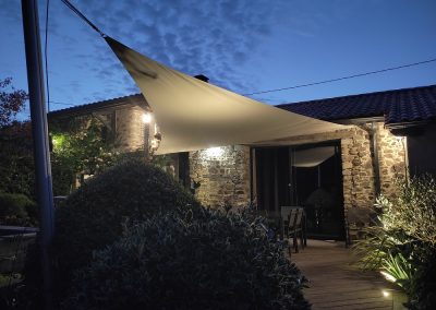 Toile d'ombrage sur mesure avec parement de pierre et éclairage mural