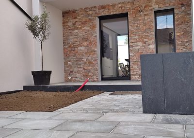 Habillage au sol avec jardinière devant une maison avec parement en pierre